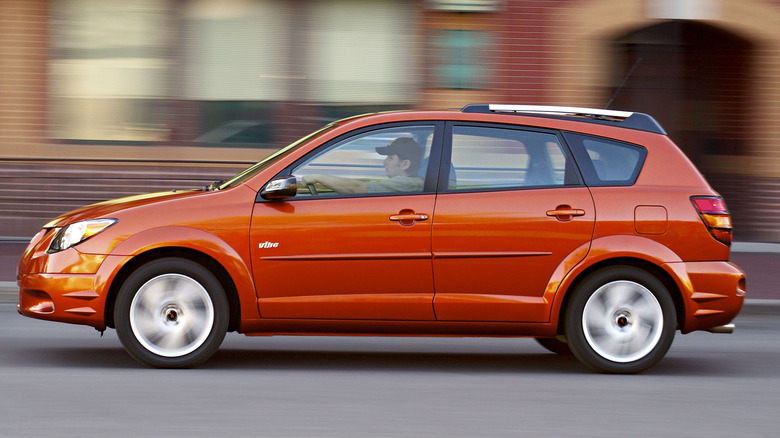 An orange Pontiac Vibe driving in a city