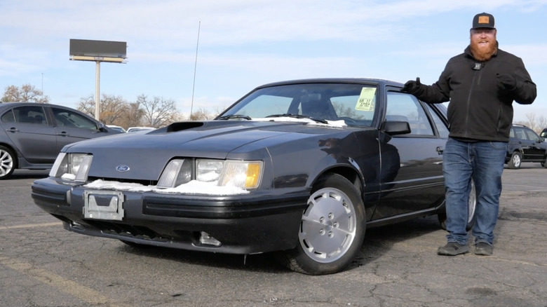 A man standing next to a 1985 Ford Mustang Fox Body SVO