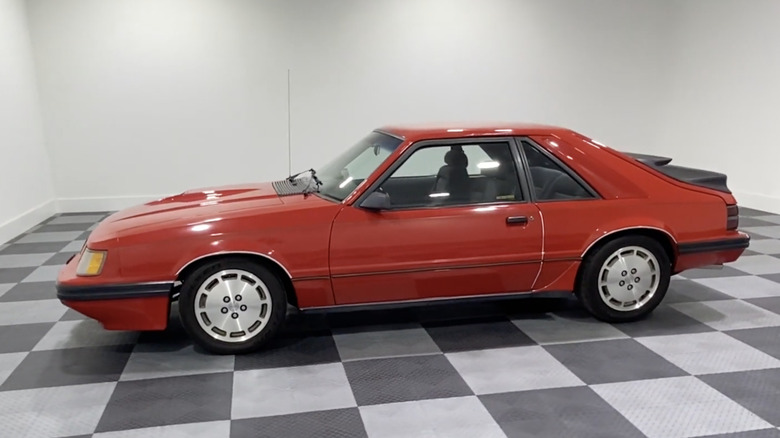 Sideview of a red 1985 Ford Mustang SVO parked in a showroom