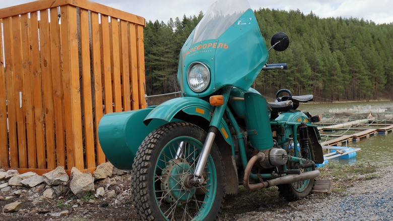 Picture of an old rusted Ural motorcycle with a sidecar.