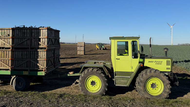Side view of Mercedes-Benz MB-Trac 1100 tractor with trailer containing wooden crates of harvested onions