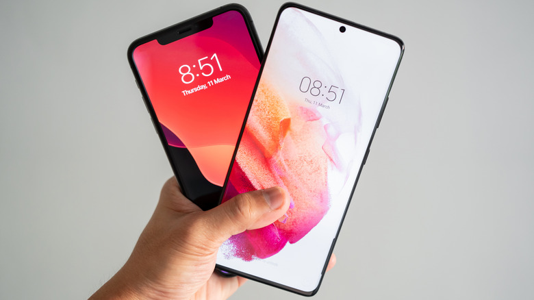 Hand holding Samsung Galaxy and Apple iPhone front view comparison