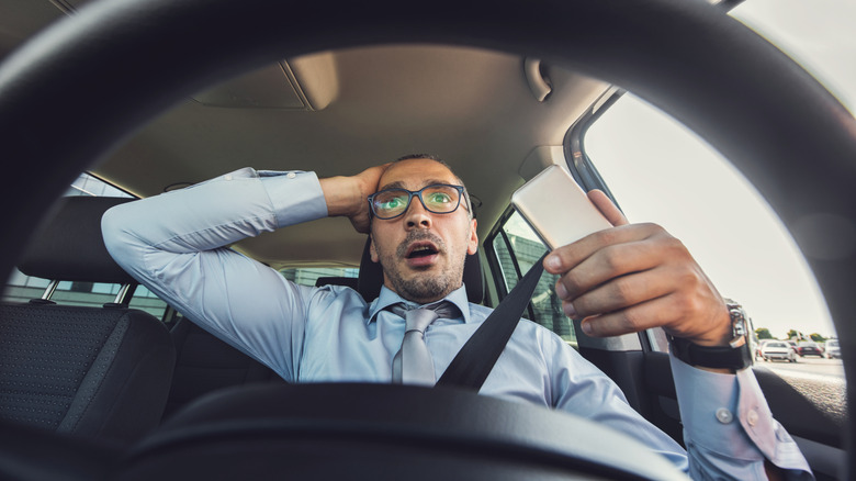 Frightened businessman using cell phone during his drive