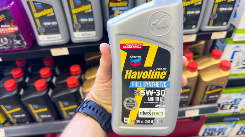 A man holding a Havoline 15W-30 Full Synthetic Motor Oil bottle