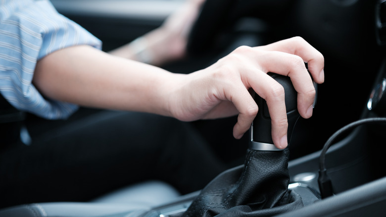 A close-up of a person holding the gear lever while driving.
