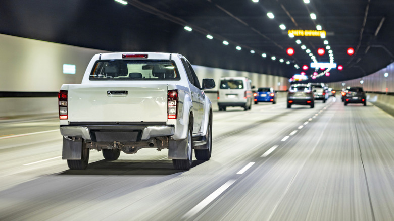 A white truck cruising in a highway tunnel.