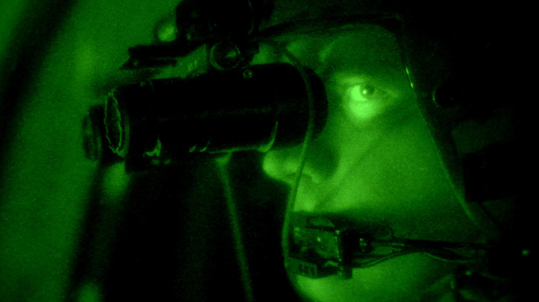 Helmet-mounted night vision goggles in typical green-hued night vision.