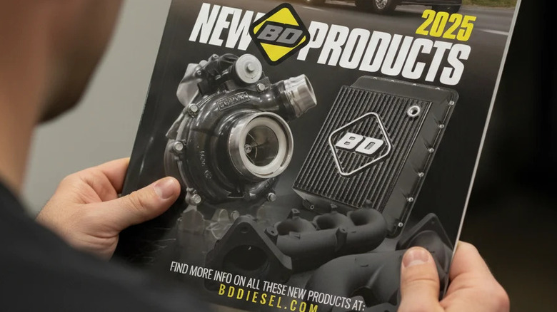 A person inspects a 2025 BD Diesel parts catalog