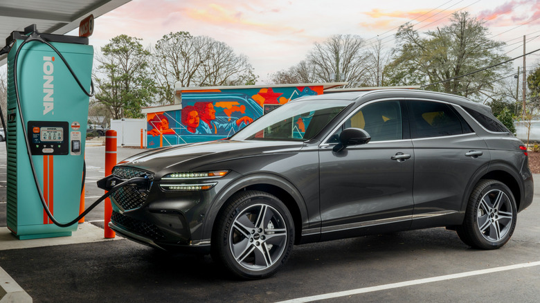 2025 Genesis GV70 SUV parked charging at a station