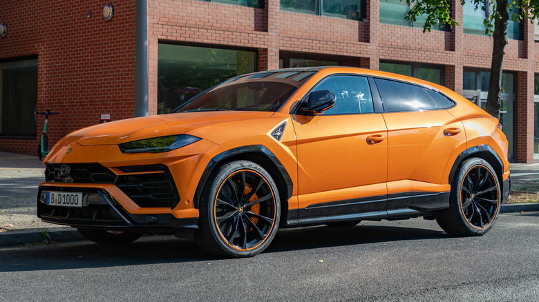A Lamborghini Urus parked in front of a brick building.