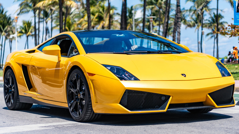 A Lamborghini Gallardo driving on a sunny road.