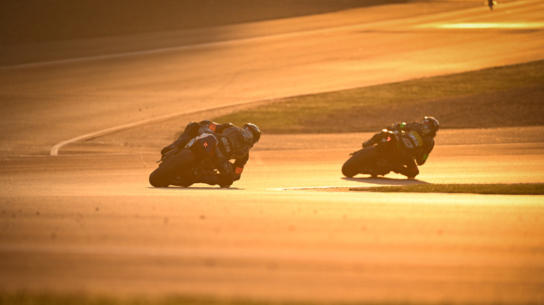 Suzuki GSXR 1000 Superstock cornering against another bike on a race track at sunset