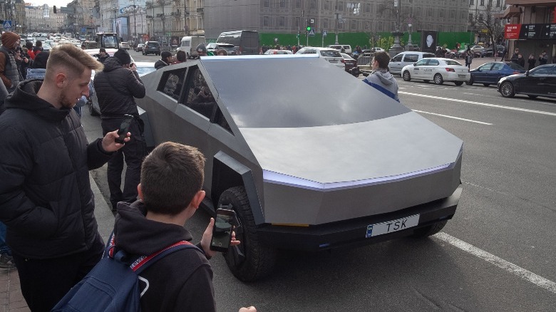 Onlookers view a Tesla Cybertruck on a busy city street
