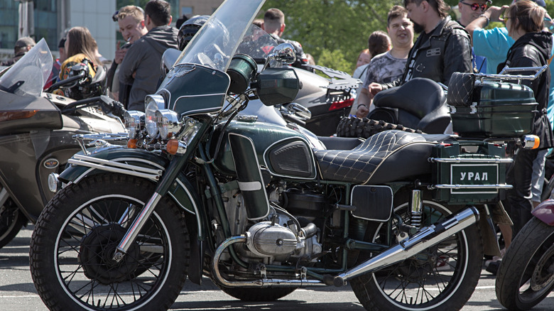 Tuned black Ural motorcycle with a sidecar in a crowded outdoor motorcycle exhibition