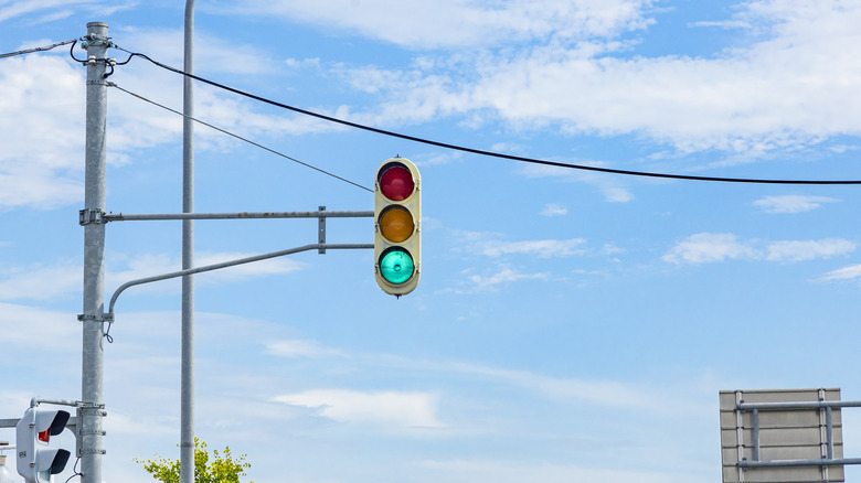 A rounded triple signal traffic light hanging on a blue sky.