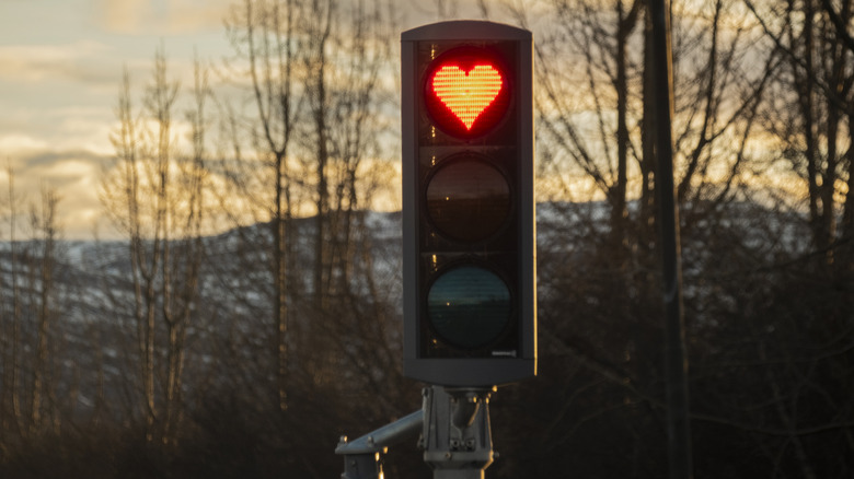 A triple signal traffic light showing a red heart at the top.