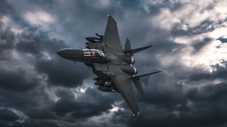 A jet fighter flying against darkening clouds