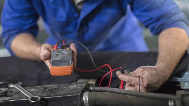 A technician testing a car battery with a multimeter