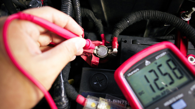 A car battery being tested with a digital multimeter
