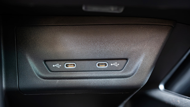 Twin USB-C ports in the center console of an unknown car with a black interior.