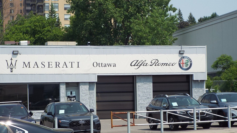 The front of a white dealership building with the Alfa Romeo and Maserati signs prominently displayed.