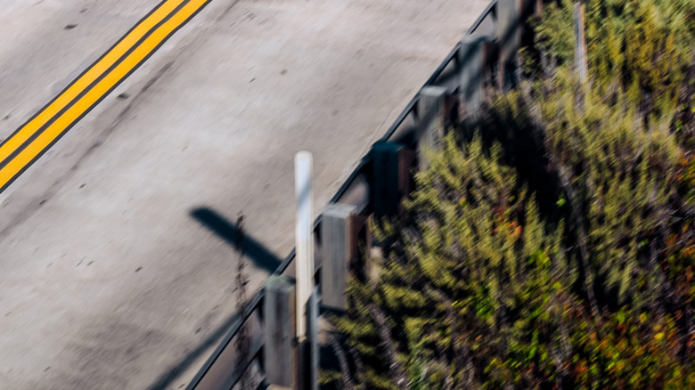 A black Koenigsegg Jeso moving down a beachside road in Monterey on an overcast day.