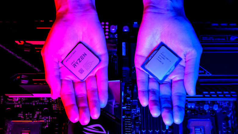 Two hands, with one holding a AMD Ryzen CPU, and the other holding an Intel Core series CPU