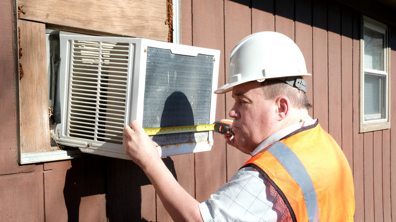 A worker installing a window AC unit