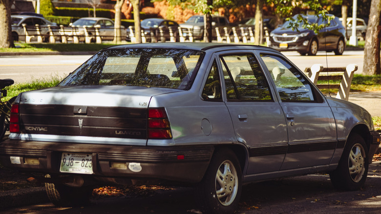 The back of a grey Pontiac LeMans SE parked in a street