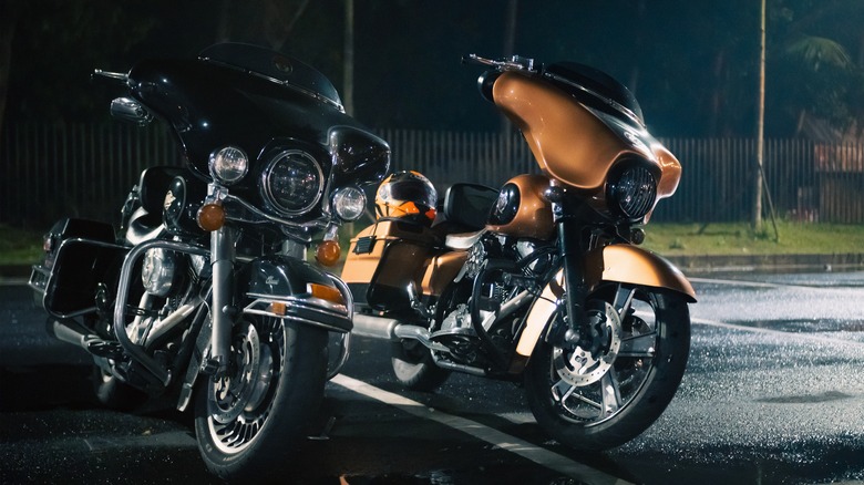 Black Harley-Davidson Electra Glide Ultra Classic and orange Harley-Davidson Street Glide Special parked on wet asphalt at night