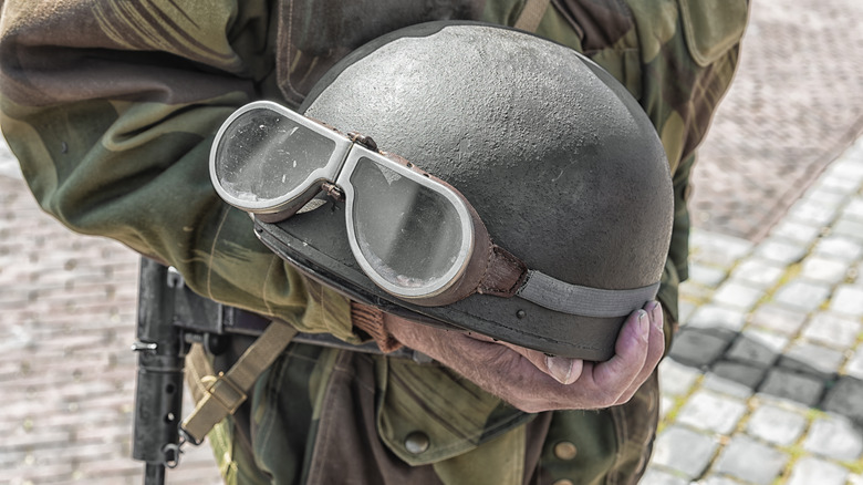 A person holding a WW2-era military motorcycle helmet.