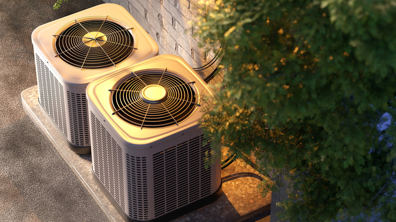 Two outdoor air conditioning units by a brick wall