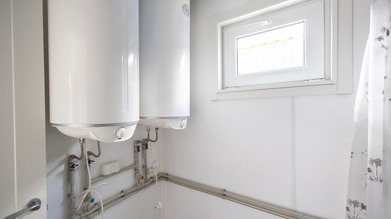 two electric water heaters mounted on a wall in a utility room