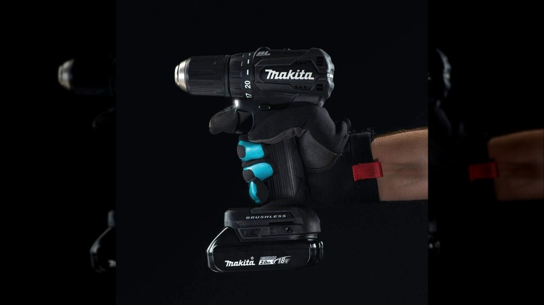 man holding Makita drill with a black background