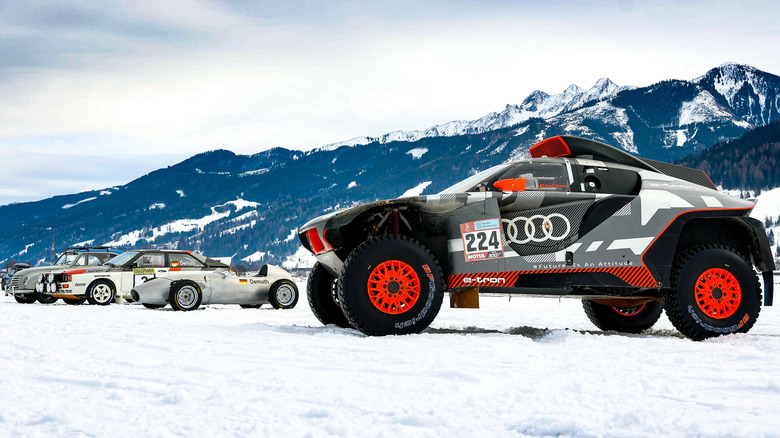 Cars sitting on snow with mountains behind them