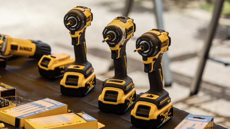 Three Dewalt drills on table edge
