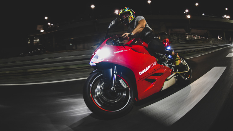 Man riding a Panigale V4 on the street at night, front 3/4 view
