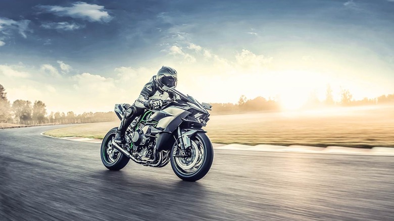 A rider on Kawasaki H2R motorcycle speeding up on empty road