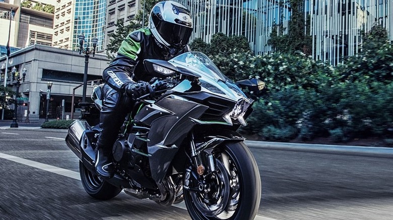 A bike rider driving the Kawasaki H2 on road with buildings behind
