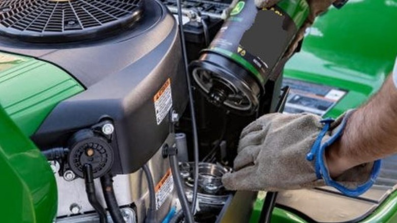 Person changing oil filter on mower