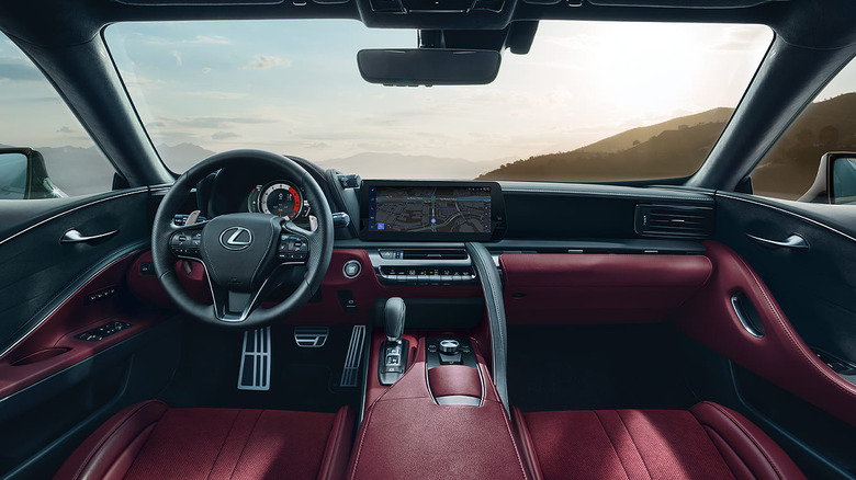 2025 Lexus LC500 interior with red leather seats, digital dashboard, and mountain view through the windshield.