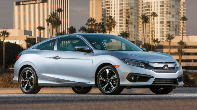 Silver 2016 Honda Civic hatchback parked with a city skyline in the background.