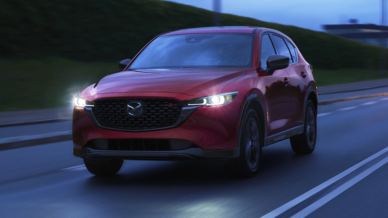 Red Mazda CX-5 driving with headlights on
