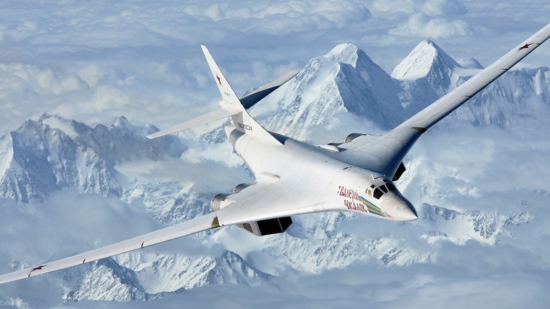 A Tupolev Tu-160 heavy strategic bomber flying over snowy mountains