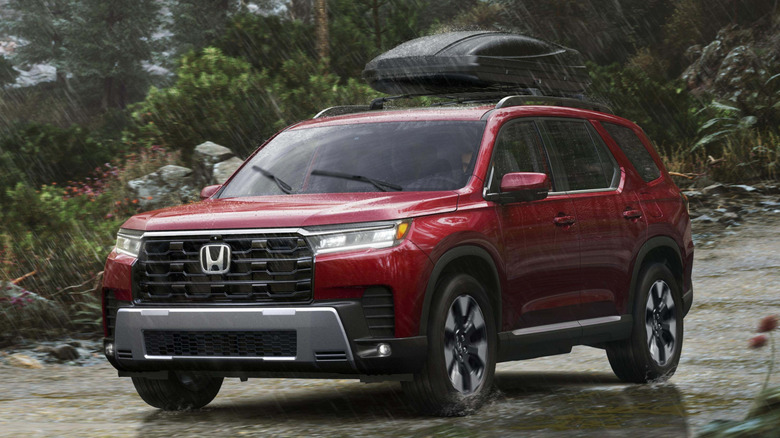 Front 3/4 view of Honda Pilot driving on shallow stream in wooded area