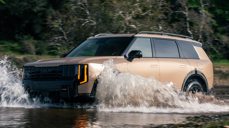Front 3/4 view of Kia Telluride traversing a stream in a wooded area