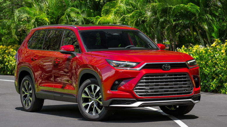 Front 3/4 view of Toyota Grand Highlander on tarmac in forested setting