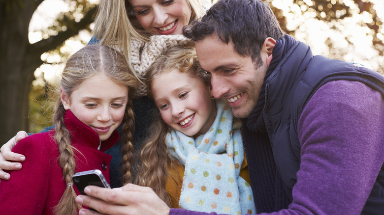 A smiling family looking at a cell phone