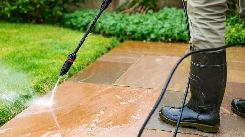 A man cleaning his patio using a pressure washer