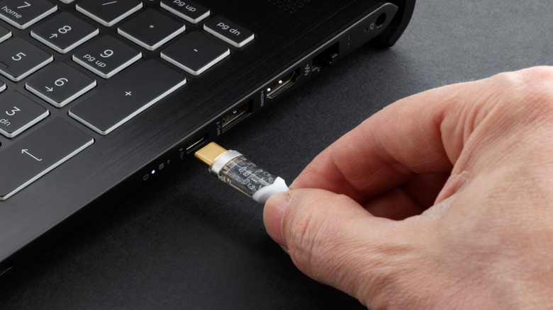 A person connecting white USB Type C connector to laptop